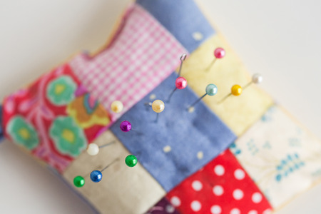 close-up on sewing tools, patchwork, tailoring and fashion concept - macro top view on colorful stitched pincushion with many beautiful pins, selective focus, flat layの写真素材
