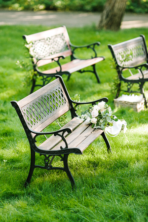 flower arrangement, ornamental flowers, marriage concept. beautiful bouquet of bride with white silk ribbon lying on the brown garden bench forgotten by its hostesseの写真素材