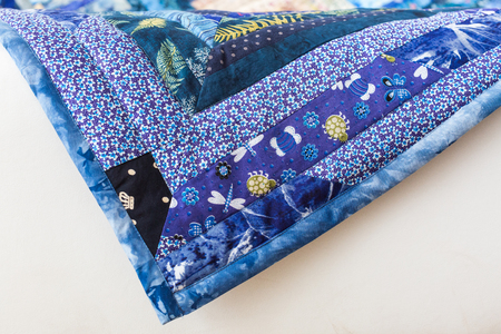 sewing, homemade, tradition, applique, garment industry, skill, creativity, cosiness concept - corner of beautiful handmaded plaid in blue shades made in asian technique of patchworkの写真素材