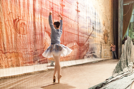 decoration, backstage, theater. man with camera taking photos of magnificent ballerina wearing for rehearsal in tutu and blue tracksuit top trying few movementsの写真素材