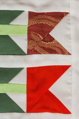 patchwork, sewing, fashion concept - macro on beautiful quilt sewn from scraps of colored cloths in feed of certain geometric shapes, close-up on different flaps of stitched material, flat layの写真素材