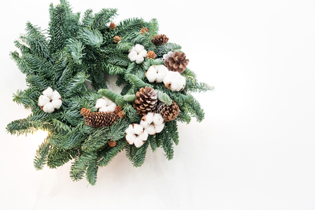 winter, crafting, nature concept. with negative space, lovely wreath made by talented floral designer with the use of conifer branches, small pinecones and pieces of cotton for creating white flowersの写真素材