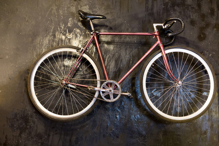 vintage, fashion, lifestyle concept. there is bicycle that is lying on black bainted floor, it is old fashioned model with high triangle model of frame of bronze colour and curved handbarsの写真素材