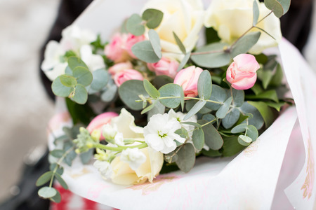 floral arrangement, wedding, surprise concept. close up of bouquet wrapped in white craft paper, it is collected of extremely beautiful and delicate flowers, pink roses and few white onesの写真素材
