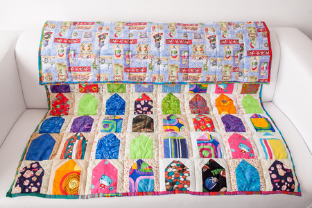 interior, quilting, handcraft concept. on the small couch of light creamy colour there is extremely...