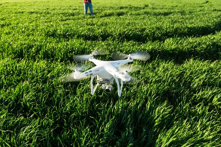 RUSSIA, ROSTOV-ON-DON - APRIL 20, 2017: white low-flying drone, on the background of green grass and the operator in the distanceのeditorial素材