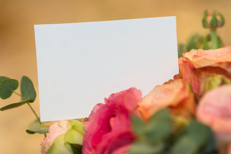 celebration, congratulation, romance concept. close up of blank white greeting card placed among blooming flowers of great bouquet, it is clean and prepared for signingの写真素材
