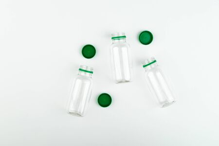 Three open empty transparent plastic jars with green caps on a white background, top view.の写真素材