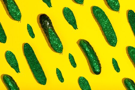 From above creative composition of sparkling shiny green cucumbers of different sizes on yellow backgroundの写真素材