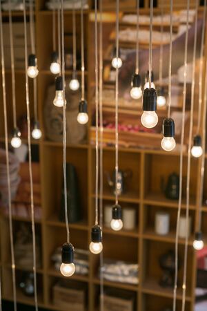 Set of incandescent lamp bulb hanging from the wall against a white brick wall. Large decorative art of lightning. Home decoration concept.の写真素材
