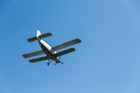 Retro biplane flying at high speed high in the air against a blue, cloudless sky. copy paste space.
