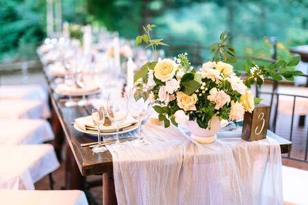 Festive outdoor wedding celebration table covered with natural tablecloth and beautifully and neatly...