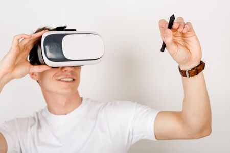 Young man developer using virtual reality headset interacts with augmented things orienting in three...