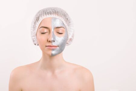 Izolated from white background crop of blindfolded pretty woman with silver mask apply on half her...