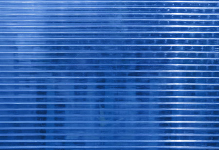 Blue polycarbonate surface with  objects behind.  Industrial background, regular structure with horizontal structure. Plastic texture with place for text.の写真素材