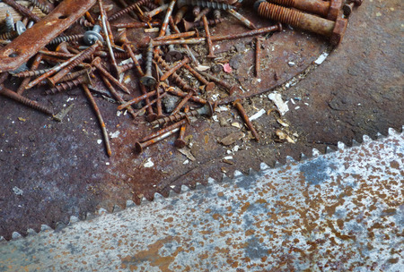 Old rusty texture with different screws and big saw blade. Aged metal - industrial background with place for text. Dirty steel surface in workshop.の写真素材