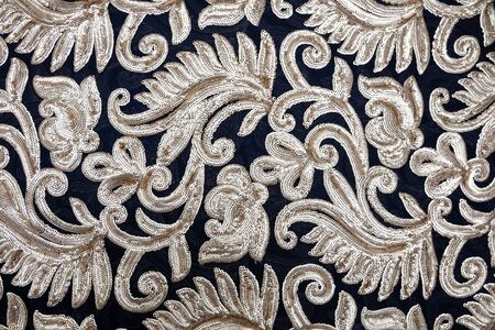 Blue fabric with patterns of silver beads in the form of flowers and branches with leaves spread out on the table. Materialの写真素材