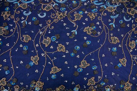 Blue fabric with colorful beads and beaded patterns spread out on the table. Materialの写真素材