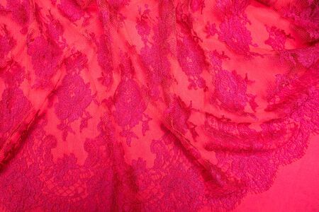 Tulle with patterns  on top of red fabric spread out on the table.の写真素材