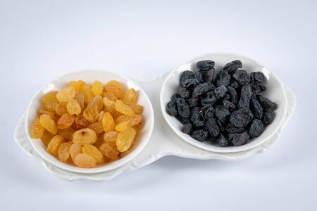 White and black raisins in  white bowls isolated on white background.の写真素材