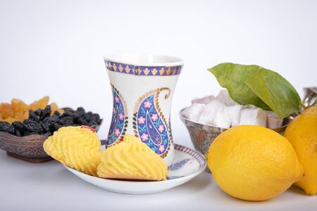 The holiday of Navruz. Traditional armudu tea Cup with national patterns and buta print. Two lemons with a branch, Turkish delight, black and white raisins in an old copper sugar bowl.の写真素材