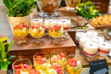 A variety of cookies in clear glass vases, fruit salads and fruit yogurts in glass cups.の写真素材