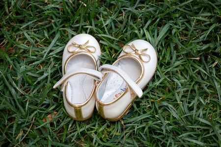 White children shoes lying on the grass.の写真素材