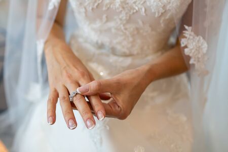 The bride in a wedding dress with a veil wearing a silver ring on the middle finger.の写真素材