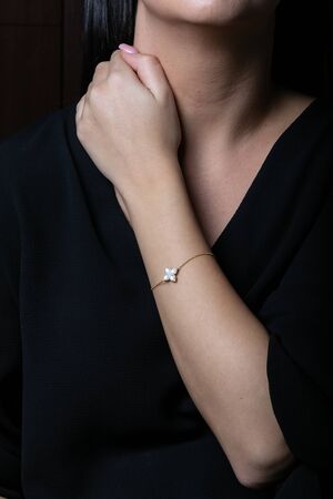 Golden bracelet on hand with stones in the shape of flower on black background.の写真素材