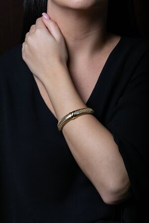 Female, wicker, yellow gold bracelet on hand, on black backgroundの写真素材