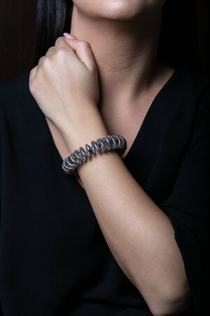 Women, silver bracelet in the shape of a spring on hand, on black background.の写真素材