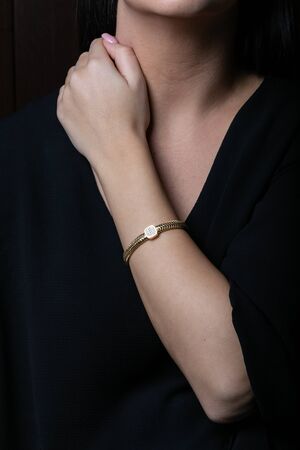 Female, wicker, yellow gold bracelet with diamonds in the middle on hand, on black background.の写真素材