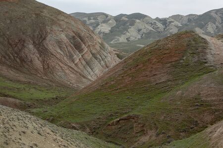 Hills and mountains covered with vegetation with red stripes on the slopes against the sky.の写真素材