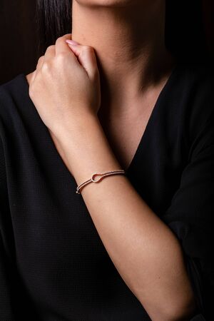 Gold female bracelet on hand with diamonds on a black background.の写真素材