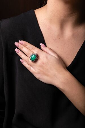 Women silver ring with diamonds and turquoise big stone in the middle on the finger, on a black background.の写真素材