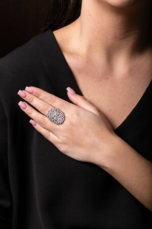 Women silver ring with stones, lots of circles on the finger, on a black background.の写真素材