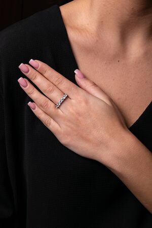 Women silver, ring with diamonds on her finger, on black background.の写真素材