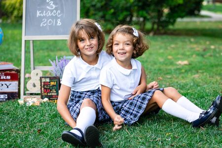 Sitting on the grass in the arms of children in white t-shirts and plaid skirts.の写真素材