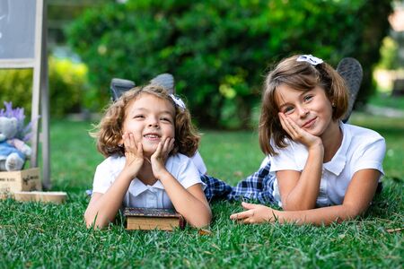 Lying on the grass in children in white t-shirts and plaid skirts.の写真素材