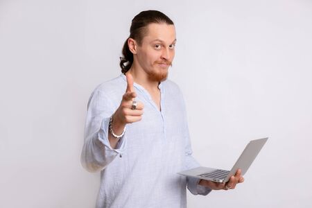 A guy in a light blue shirt holding a laptop in his hands, looking at the camera.の写真素材
