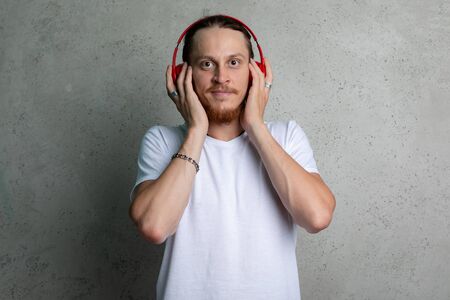 A guy in a white t shirt with red headphones on a gray background.の写真素材