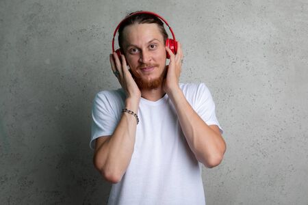 A guy in a white tshirt with red headphones on a gray background.の写真素材