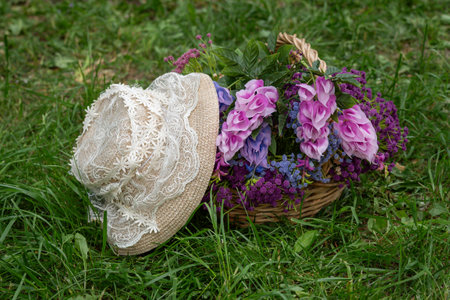 Straw Hat and Basket of Flowers on Grassの写真素材