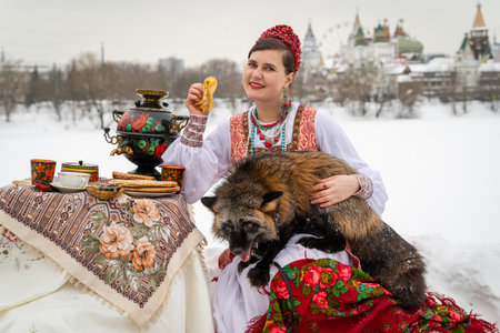 Woman Enjoying Traditional Tea with a Pet Fox Outdoorsの写真素材