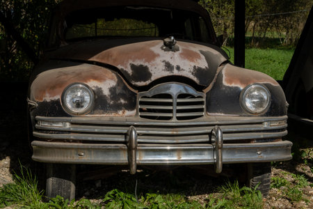 Vintage Rusty Car Front View in Dappled Sunlightの写真素材