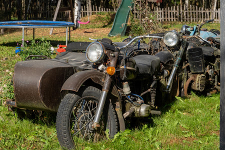 Abandoned Vintage Motorcycles in Overgrown Yardの写真素材