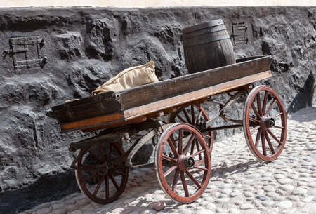 old wooden cart  with a bag and a barrel on background of old brick wallの写真素材