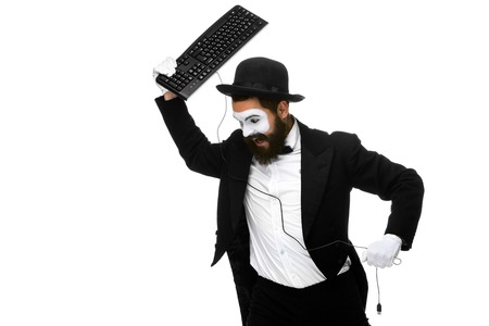 Angry mime as a businessman is destroying a keyboard. isolated on white backgroundの写真素材