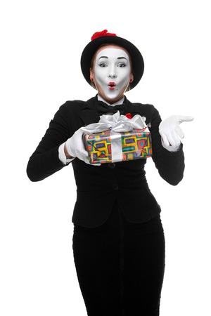 Mime as playful, joyful and excited woman with gift standing isolated on white background.の写真素材