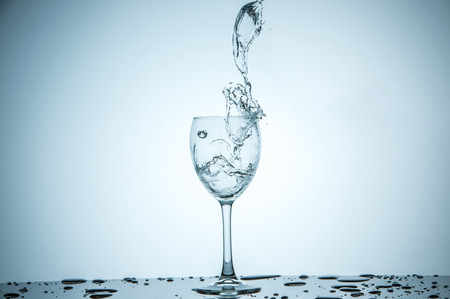 A glass being filled with water on white backgroundの写真素材